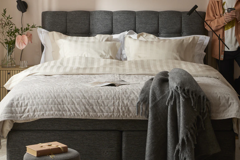 en kille står i ett sovrum med en stor säng och tittar ut genom fönstret