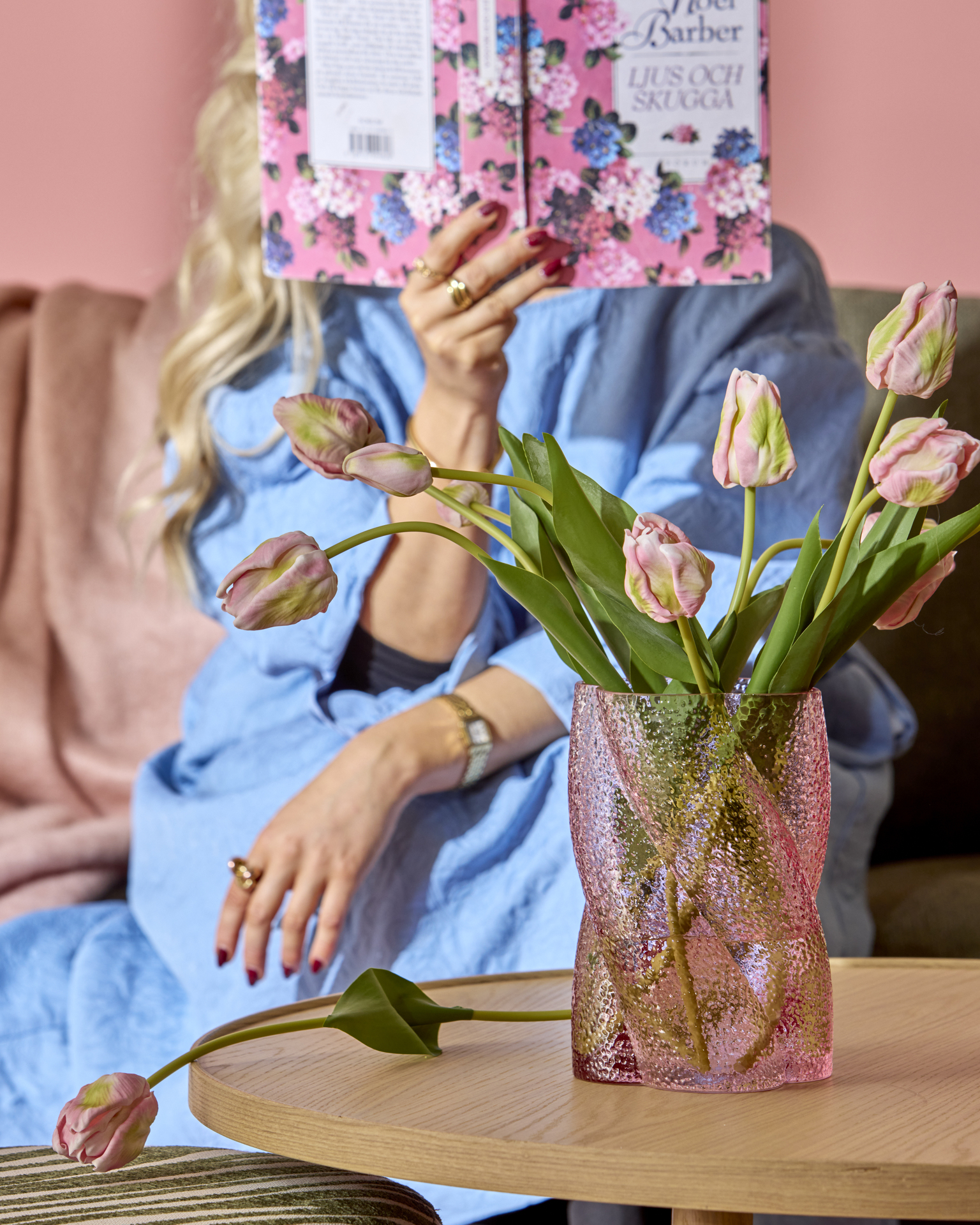 En rosa vas med rosa tulpaner står på ett soffbord i ljust trä