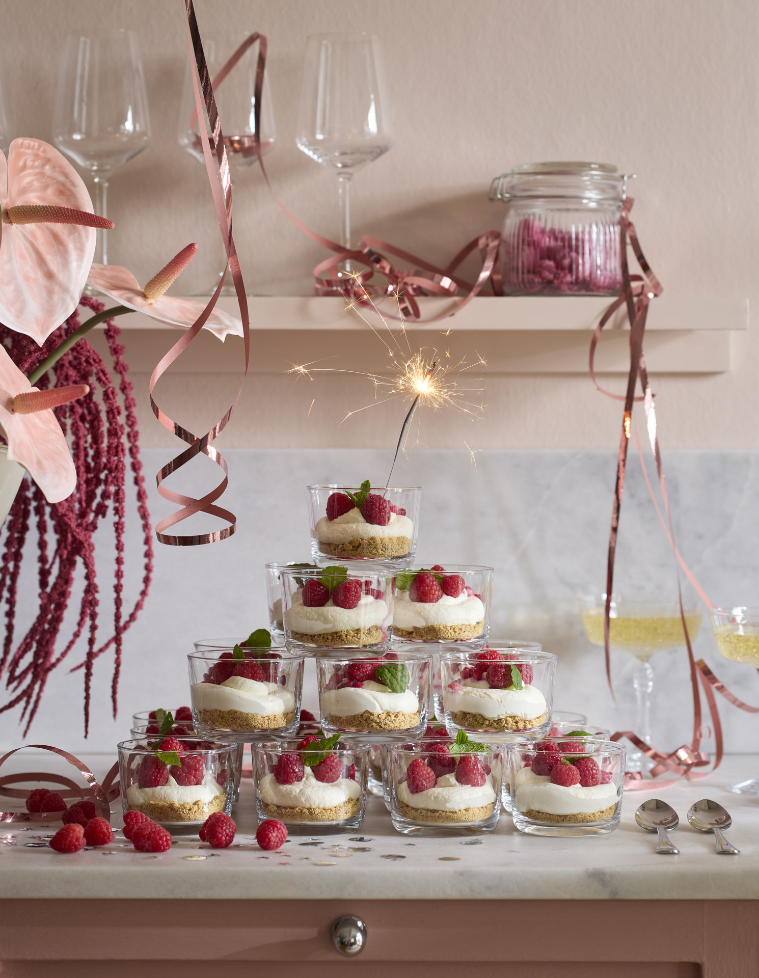 Ett festligt torn av små glas fyllda med dessert är staplade på en köksbänk
