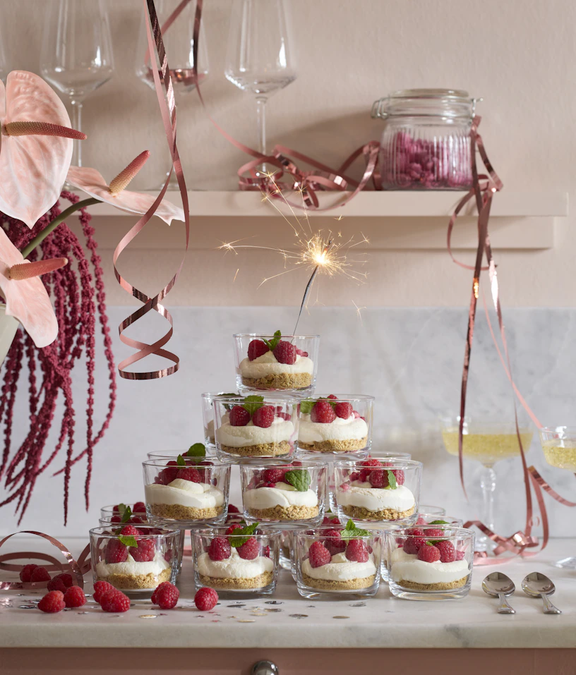 Ett festligt torn av små glas fyllda med dessert är staplade på en köksbänk