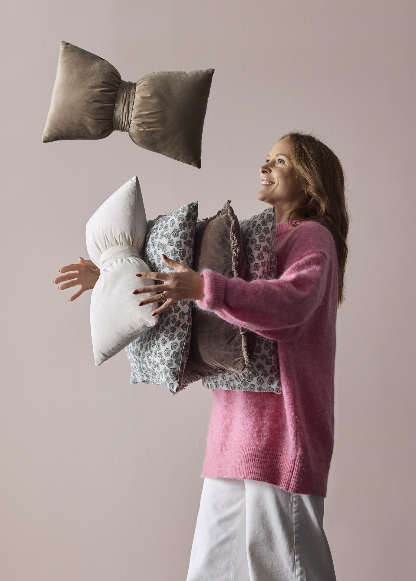 En kvinna håller i massor av prydnadskuddar