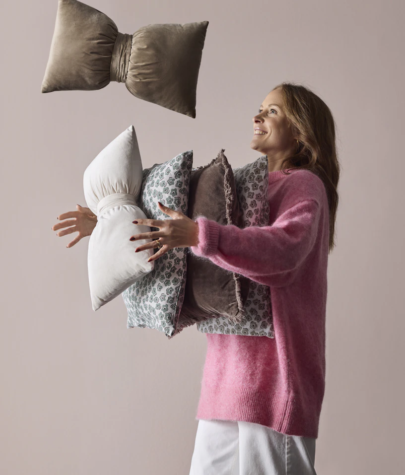 En kvinna håller i massor av prydnadskuddar