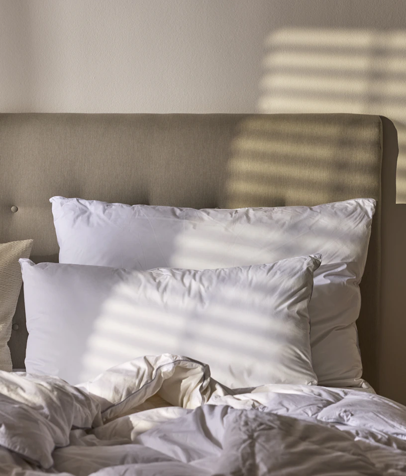 I en säng ligger två fluffiga hotellkuddar i olika storlekar