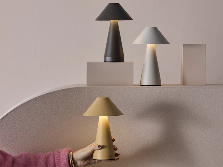 tre portabla lampor i olika färger mot en rosa bakgrund