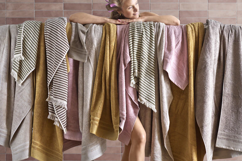 En tjej ståendes bakom massa handdukar i olika färger