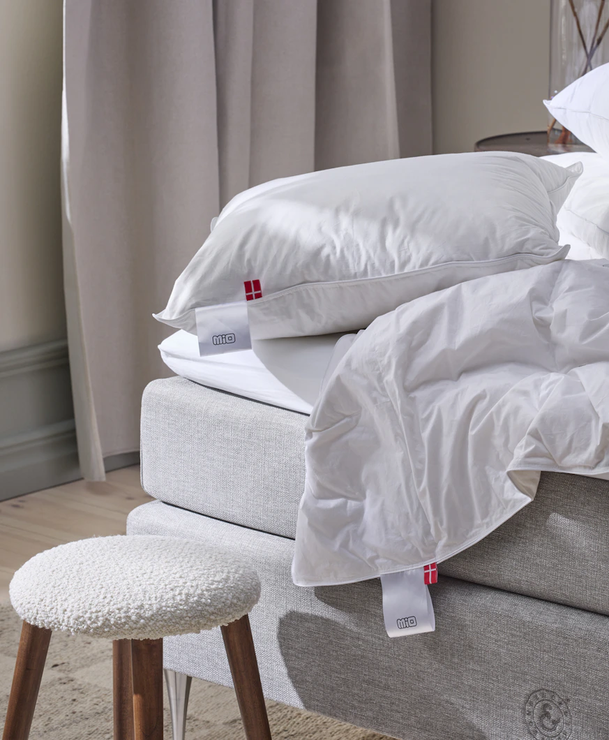 kuddar och täcken ligger på kanten av en grå säng