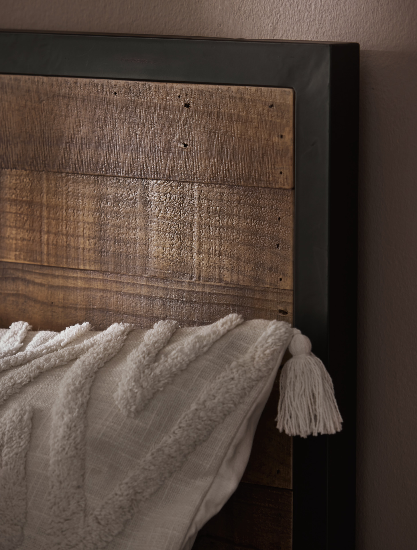 en närbild på en sänggavel i trä med en svart metallram