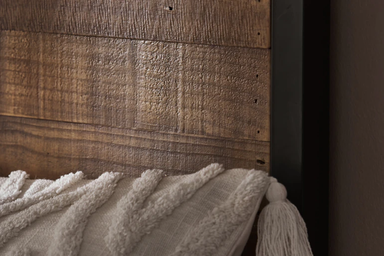 en närbild på en sänggavel i trä med en svart metallram