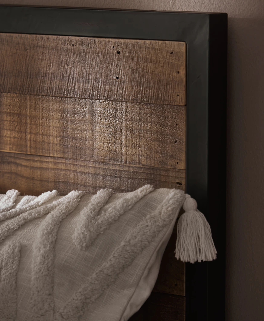 en närbild på en sänggavel i trä med en svart metallram