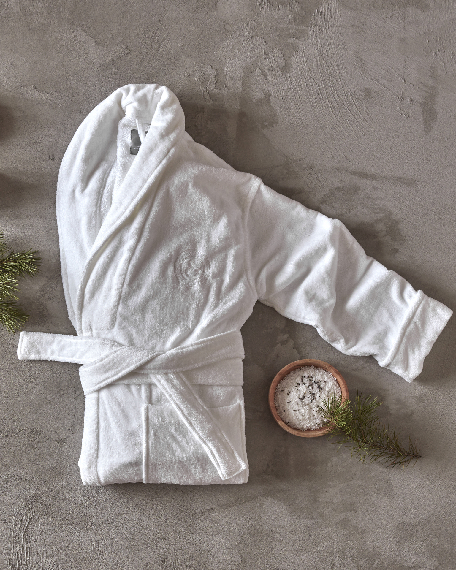 en vit morgonrock ligger ihopvikt på ett grått golv