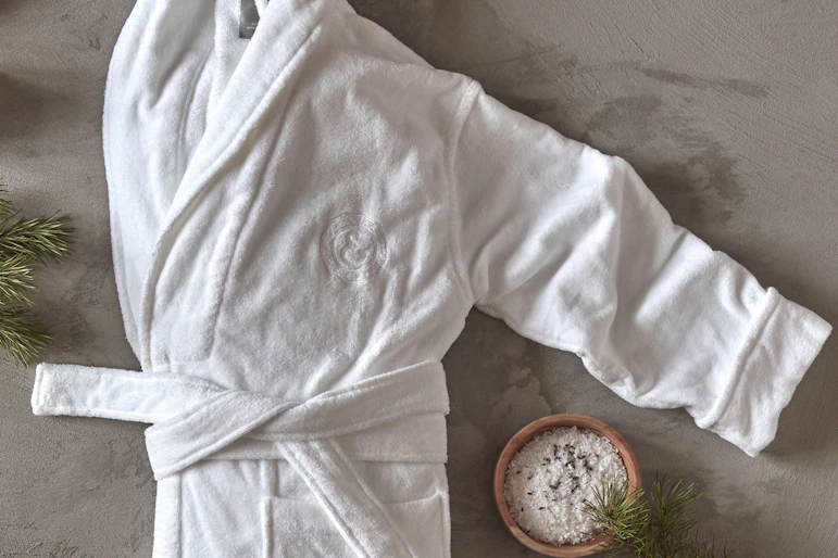 en vit morgonrock ligger ihopvikt på ett grått golv