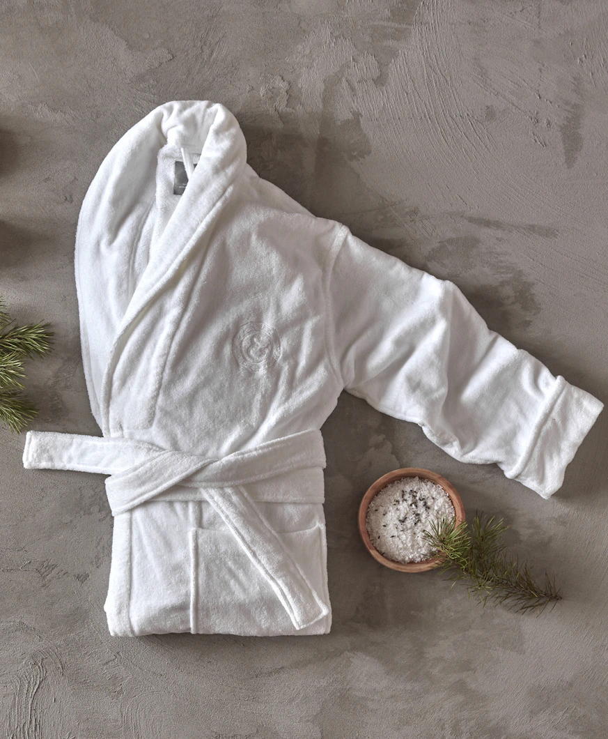 en vit morgonrock ligger ihopvikt på ett grått golv