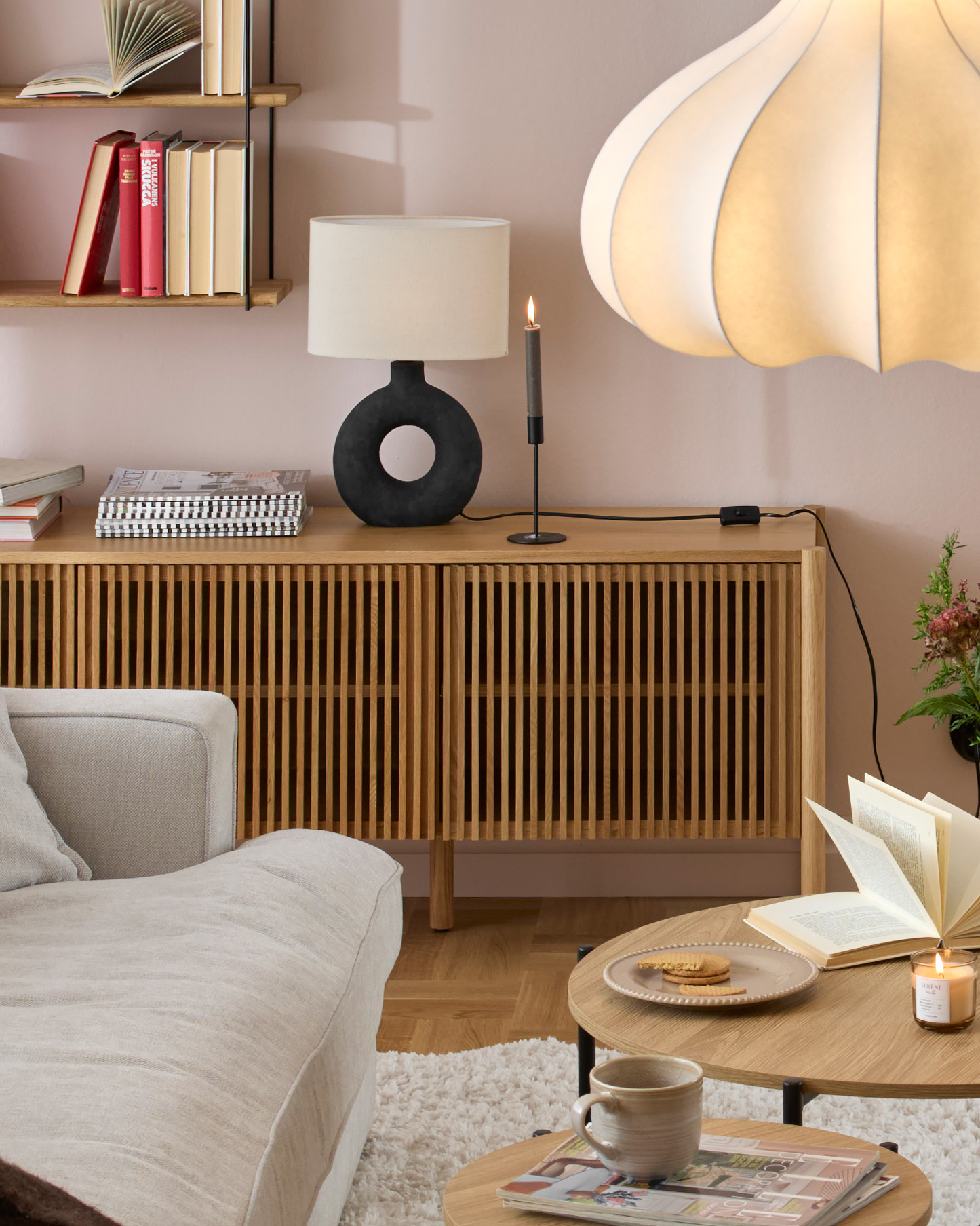 en ekfärgad tv-bänk med ribbor som luckor står framför en ljusrosa vägg