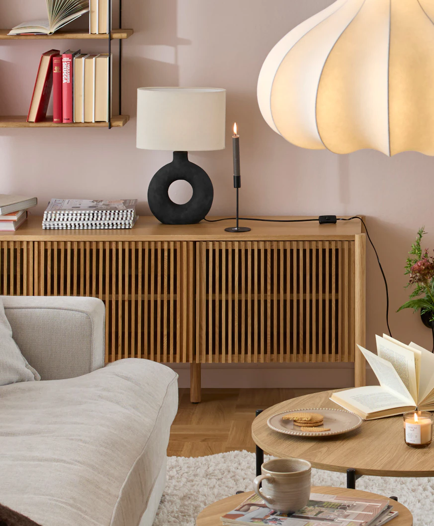 en ekfärgad tv-bänk med ribbor som luckor står framför en ljusrosa vägg