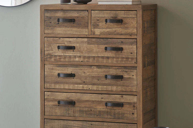 en byrå med svarta handtag står mot en grå vägg