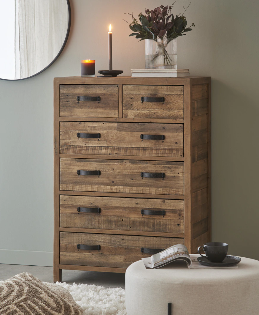 en byrå med svarta handtag står mot en grå vägg