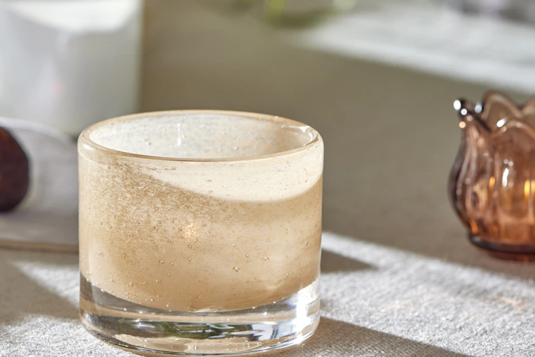 en ljusrosa ljuslykta ståendes på ett bord