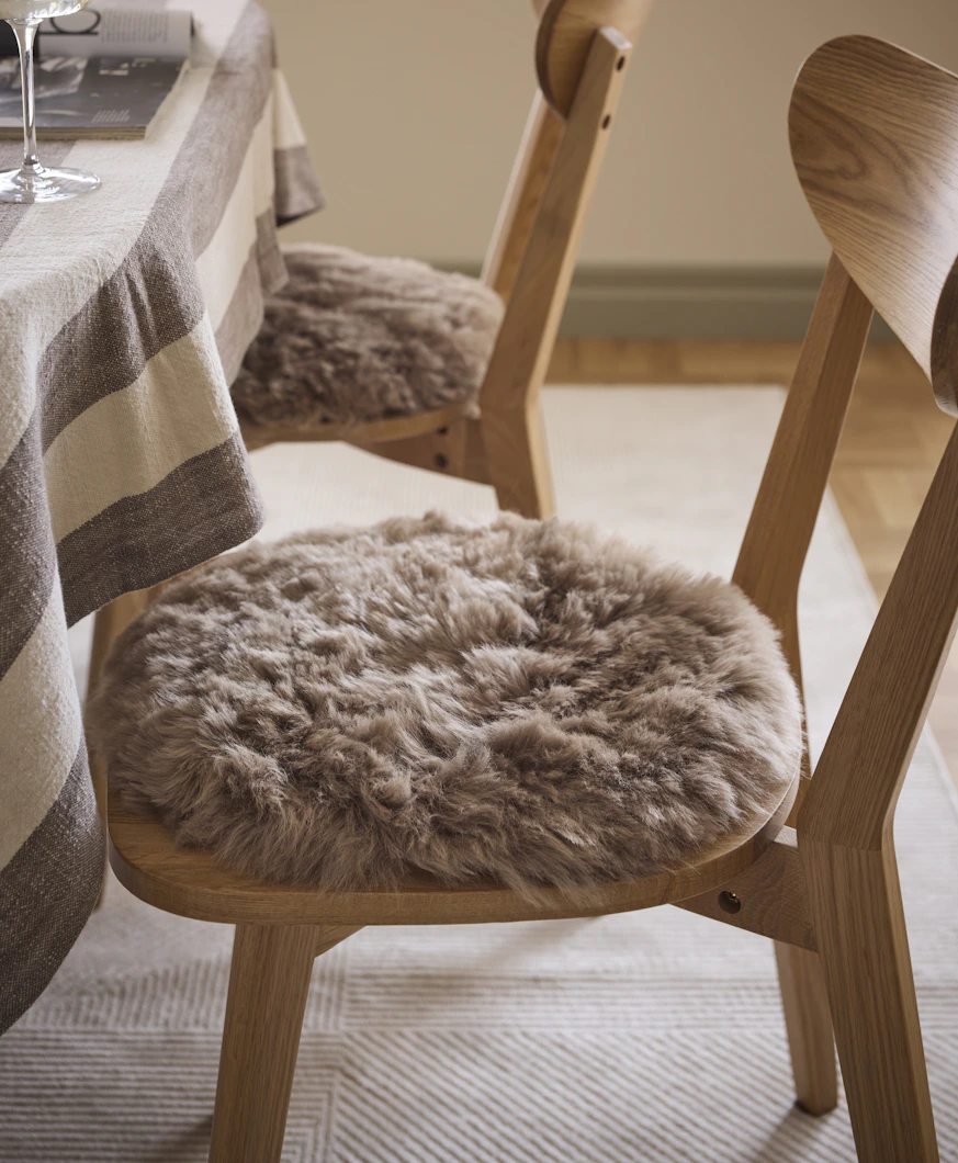en brun stolsdyna ligger på en ekfärgad stol framför ett bord