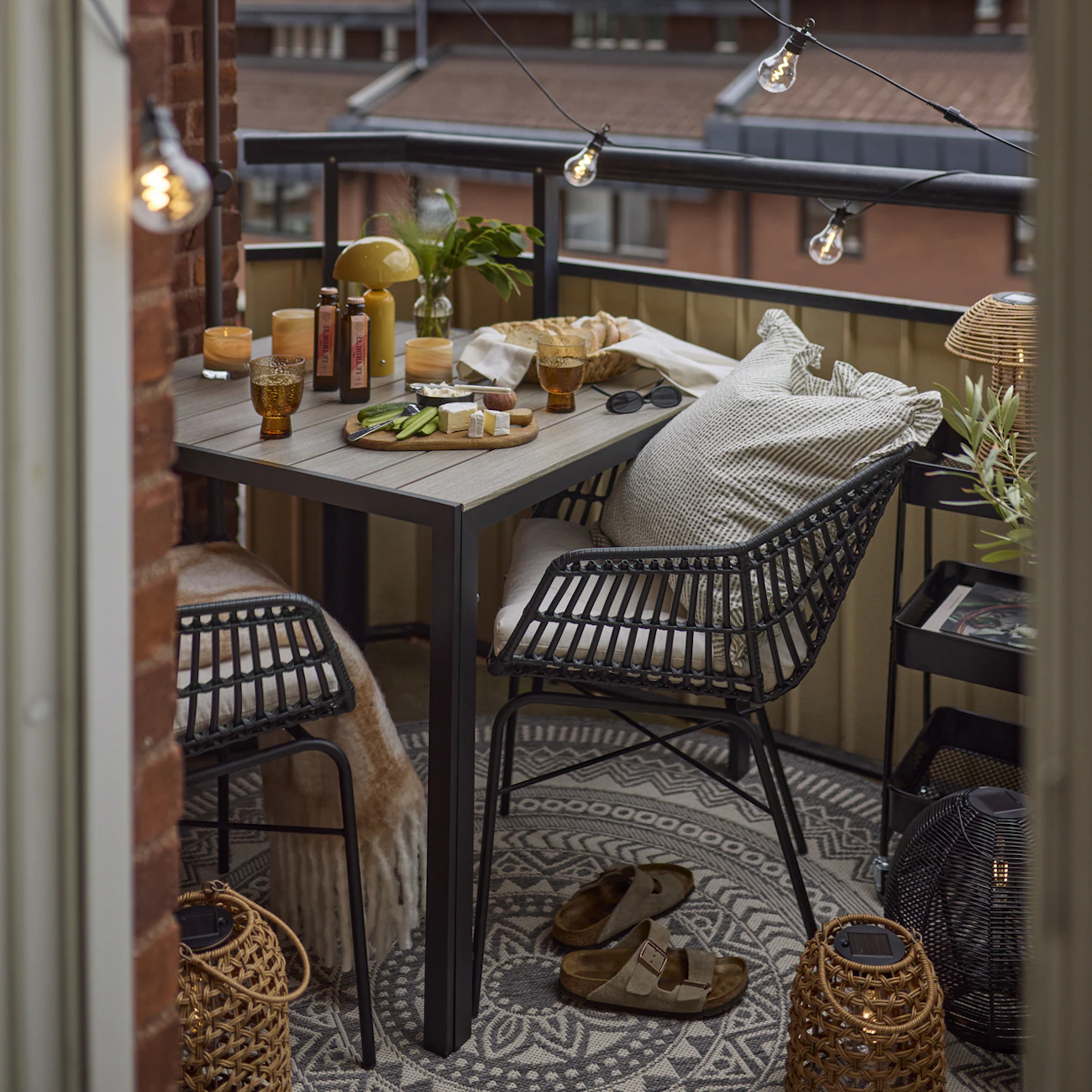 På en balkong är en sittgrupp uppdukad med en ostbricka och tända ljus.