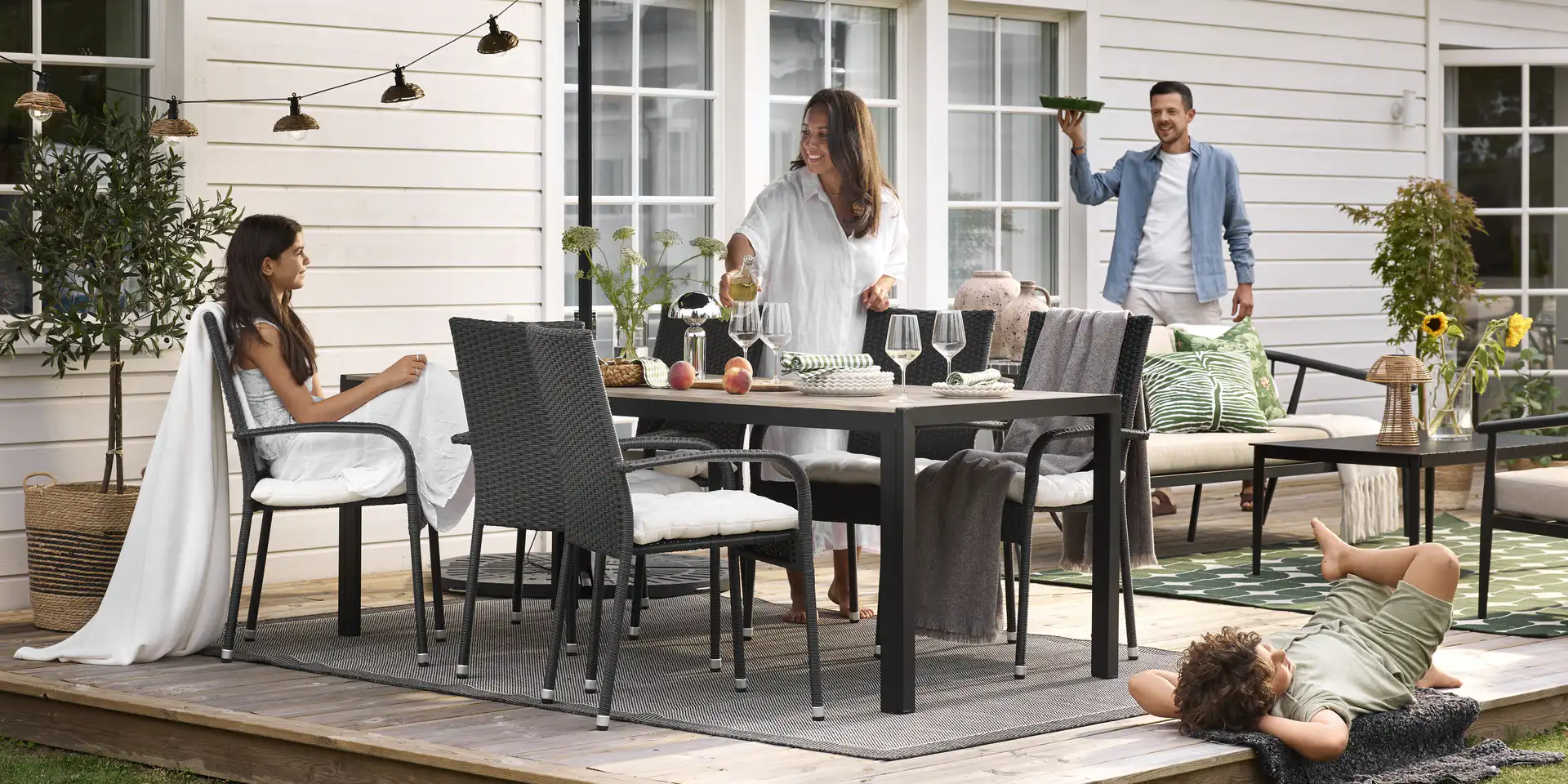 En familj sitter runt en stor utegrupp och för sig redo för kvällsmat