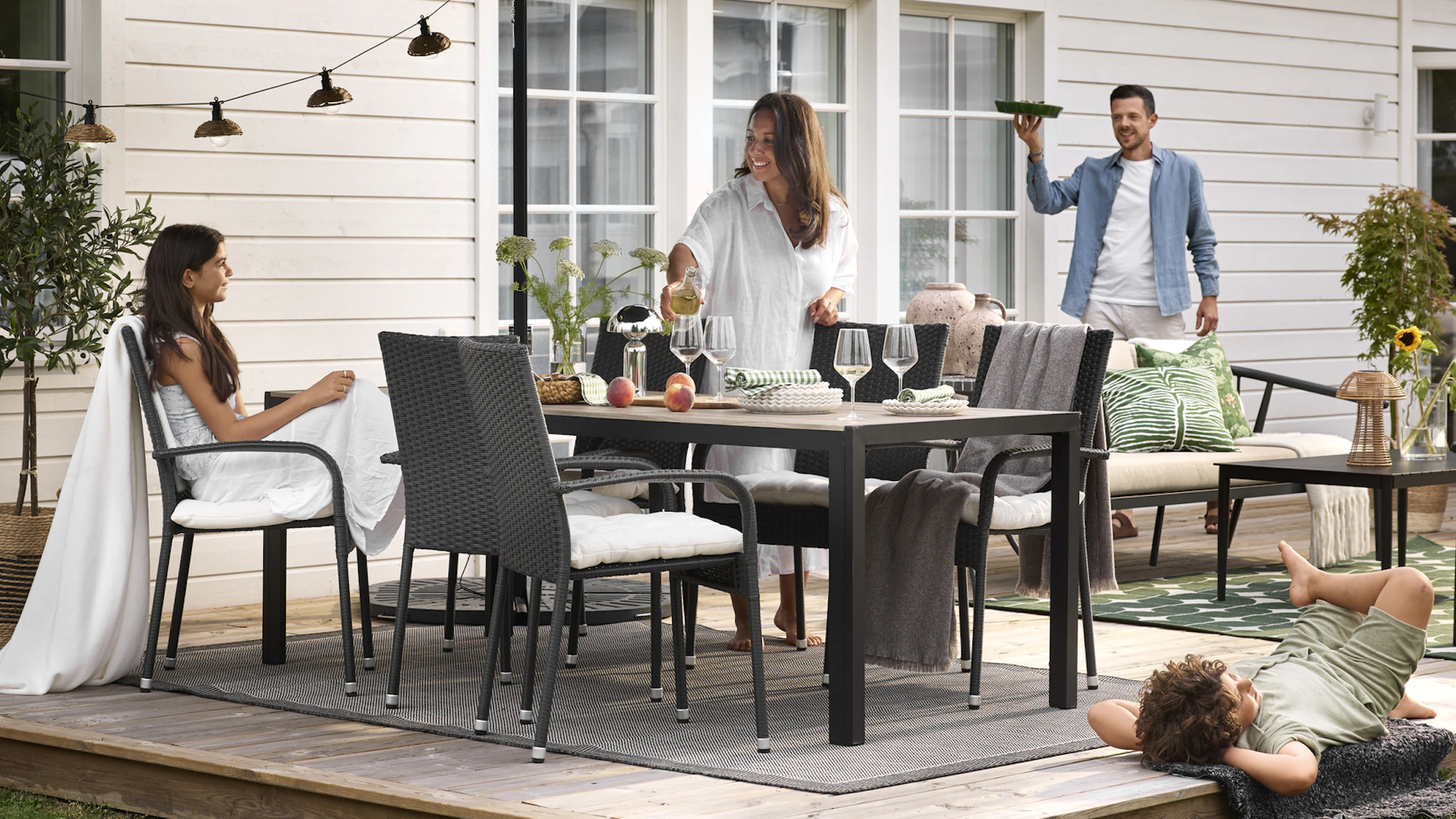 En familj sitter runt en stor utegrupp och för sig redo för kvällsmat