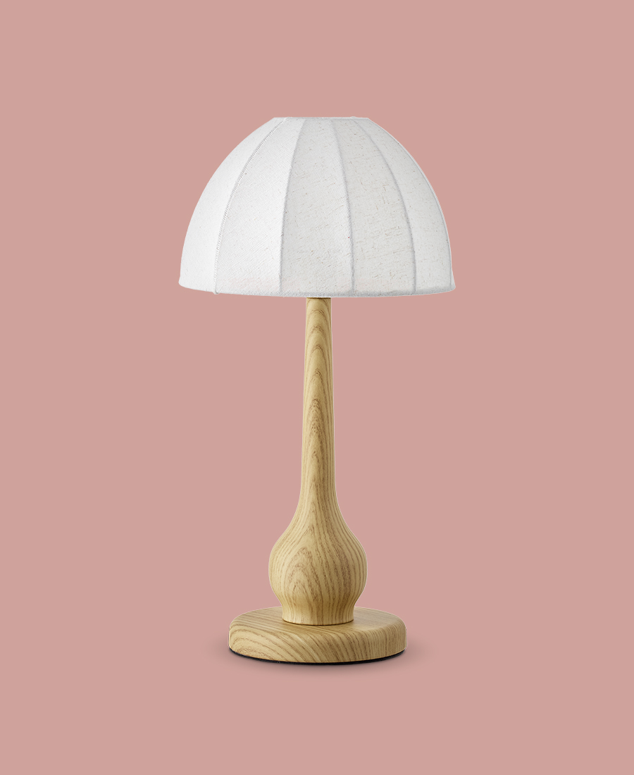 En lampfot i ljust trä med vit skärm är frilagd på en rosa bakgrund