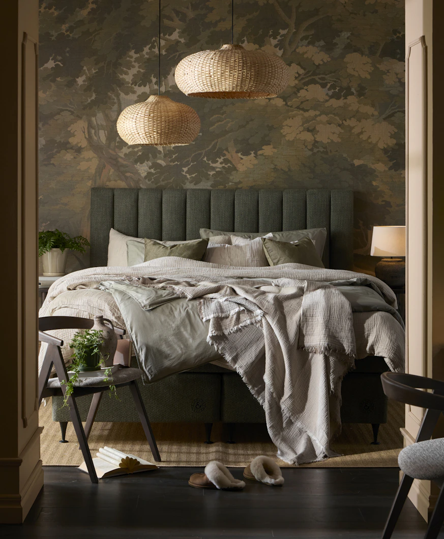 en grön kontinentalsäng står bäddad i ett mörkt sovrum