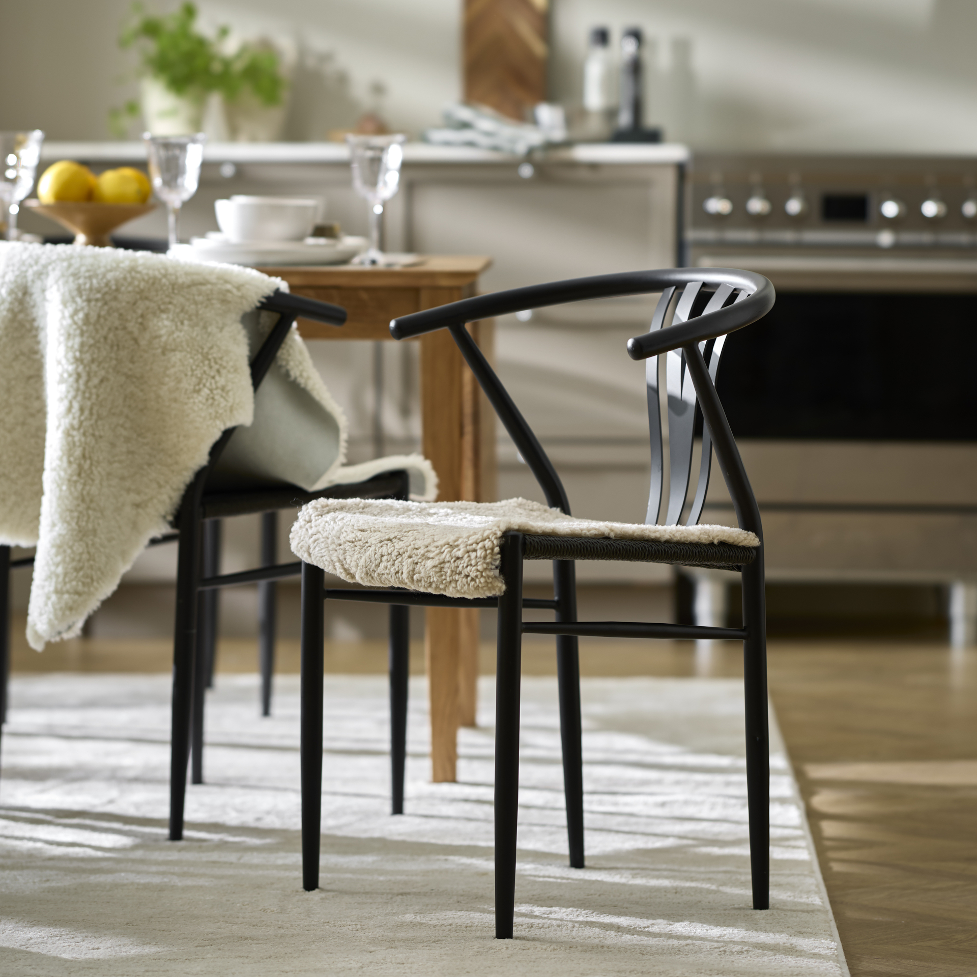 en svart stol med ett vitt fårskinn står i ett kök
