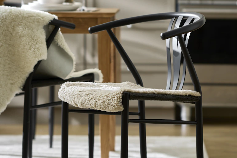 en svart stol med ett vitt fårskinn står i ett kök
