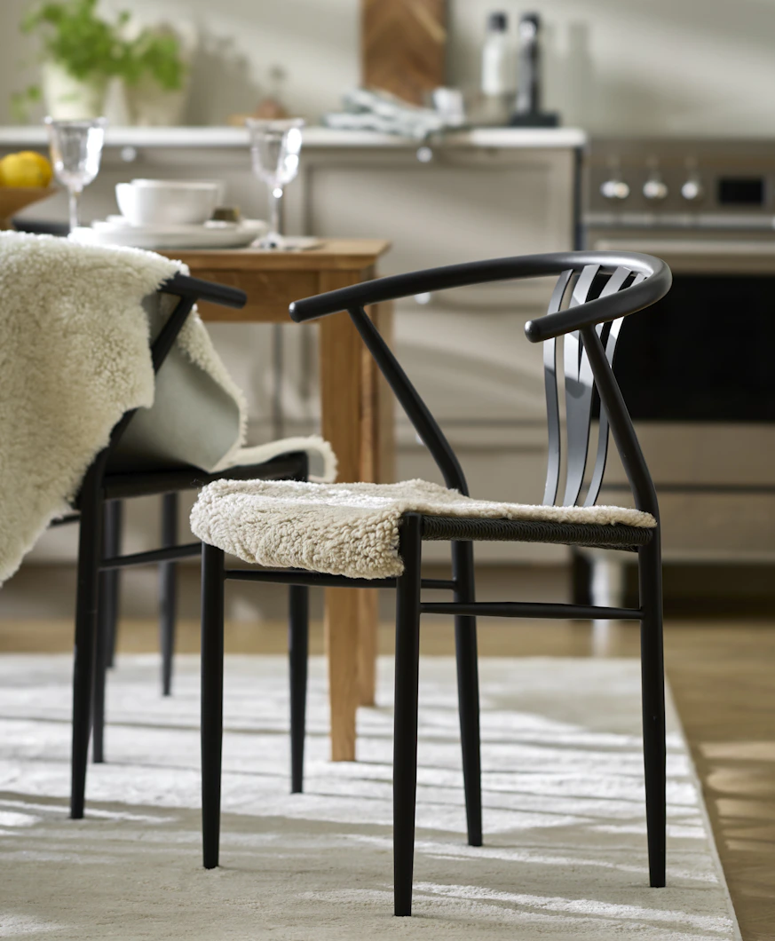 en svart stol med ett vitt fårskinn står i ett kök