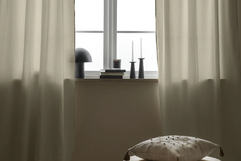 vita gardiner hänger framför ett ljus fönster