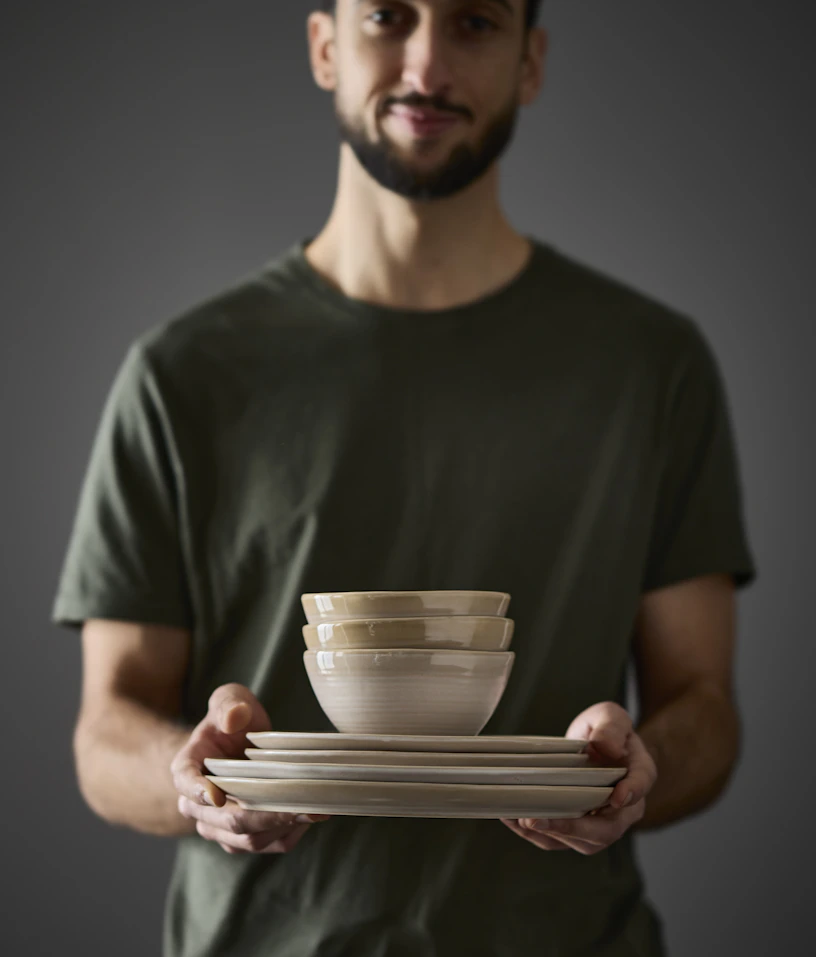 En man håller en stapel av assietter och skålar