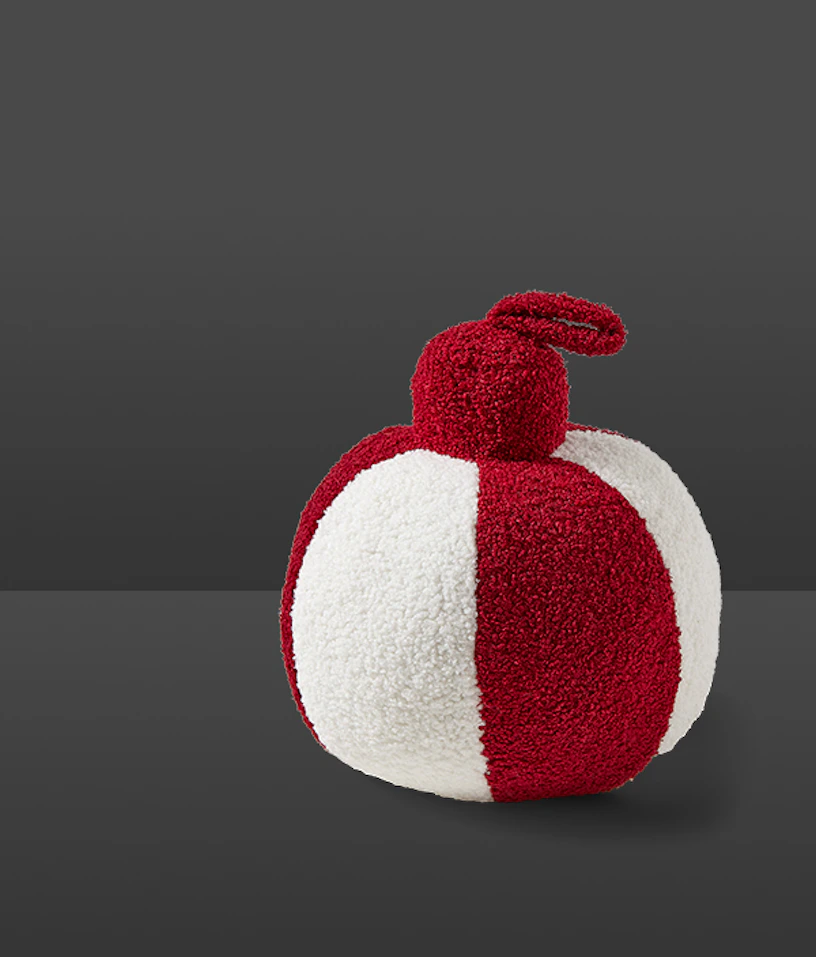 En prydnadskudde i form av en röd och vit julkula