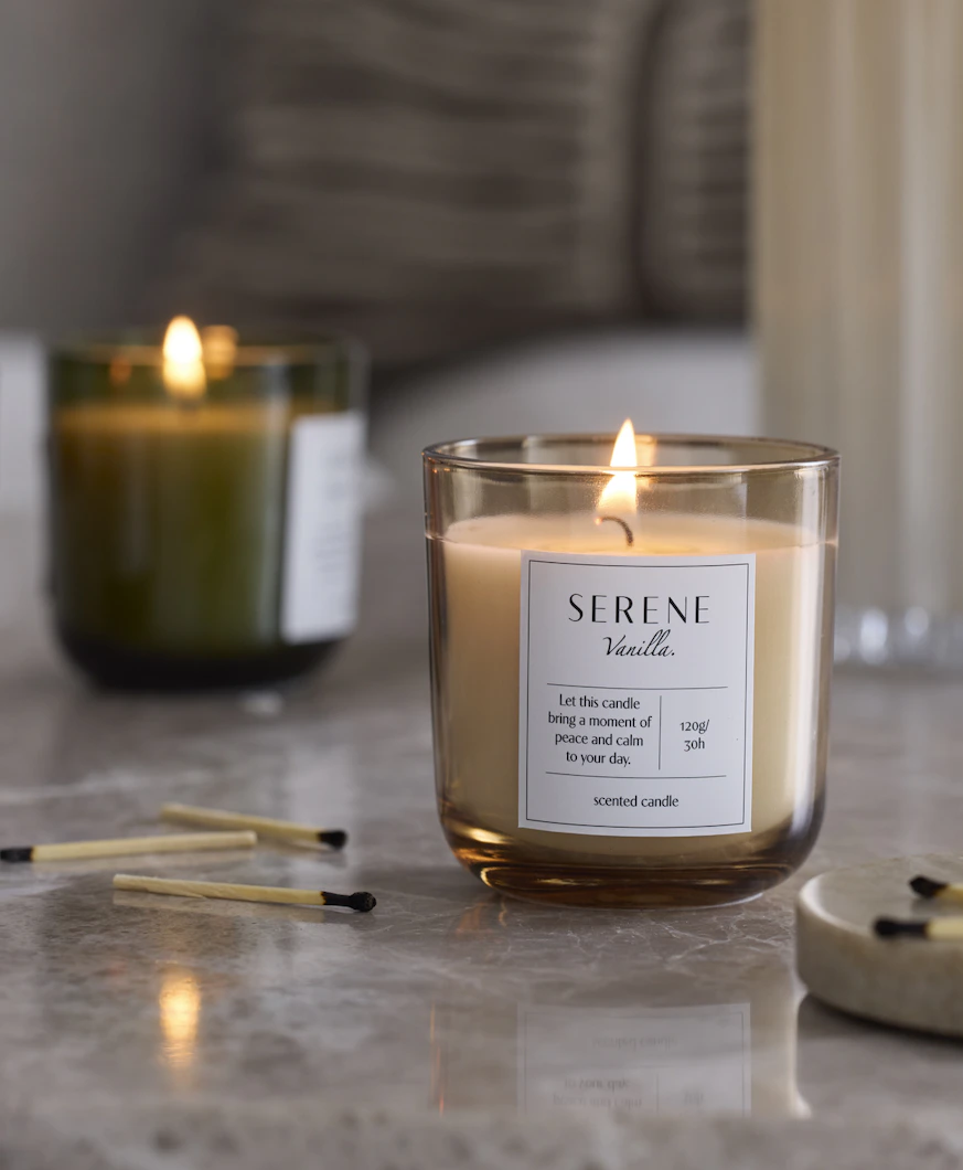 tre doftljus i olika färger står på en stenskiva