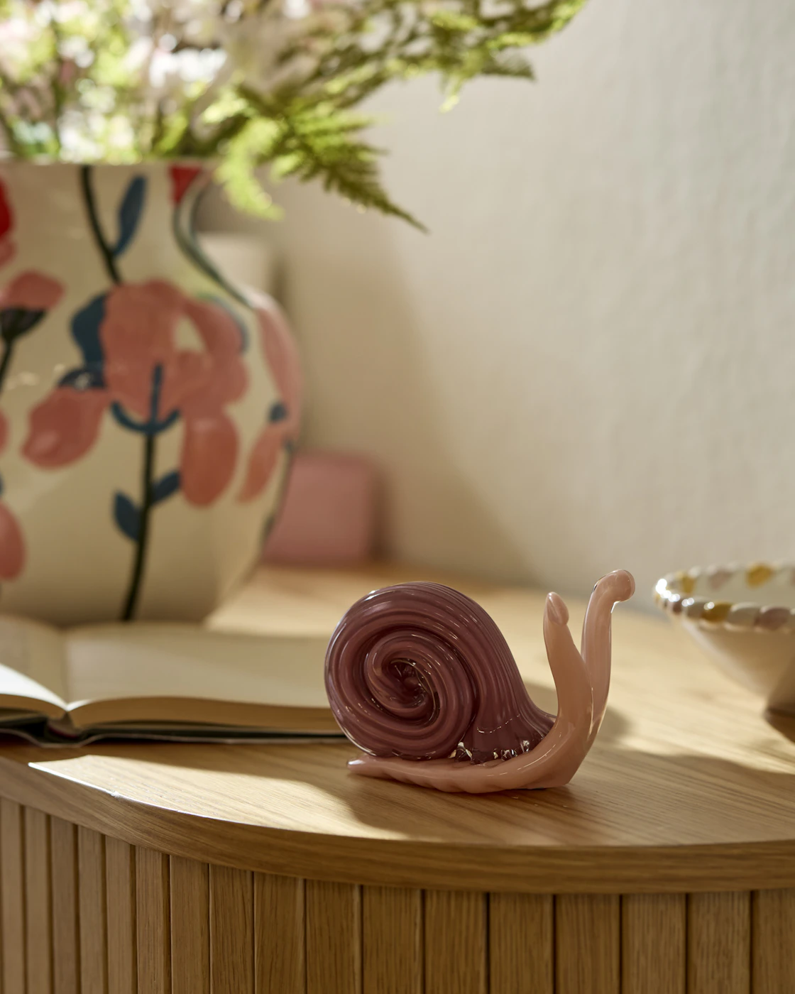 Ett prydnadsföremål i form av en rosa snigel i glas står på en skänk.