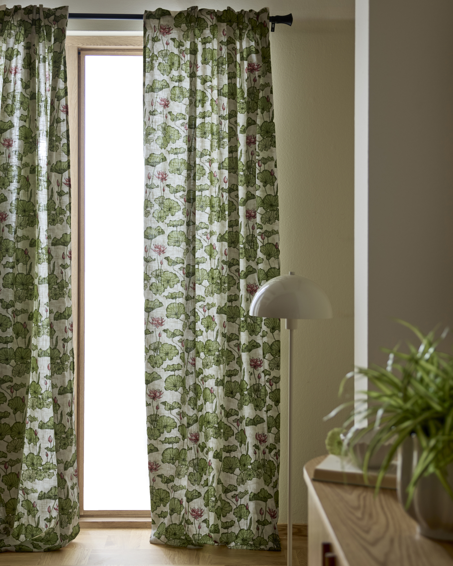 en golvlampa står bredvid ett fönster med mönstrade gardiner