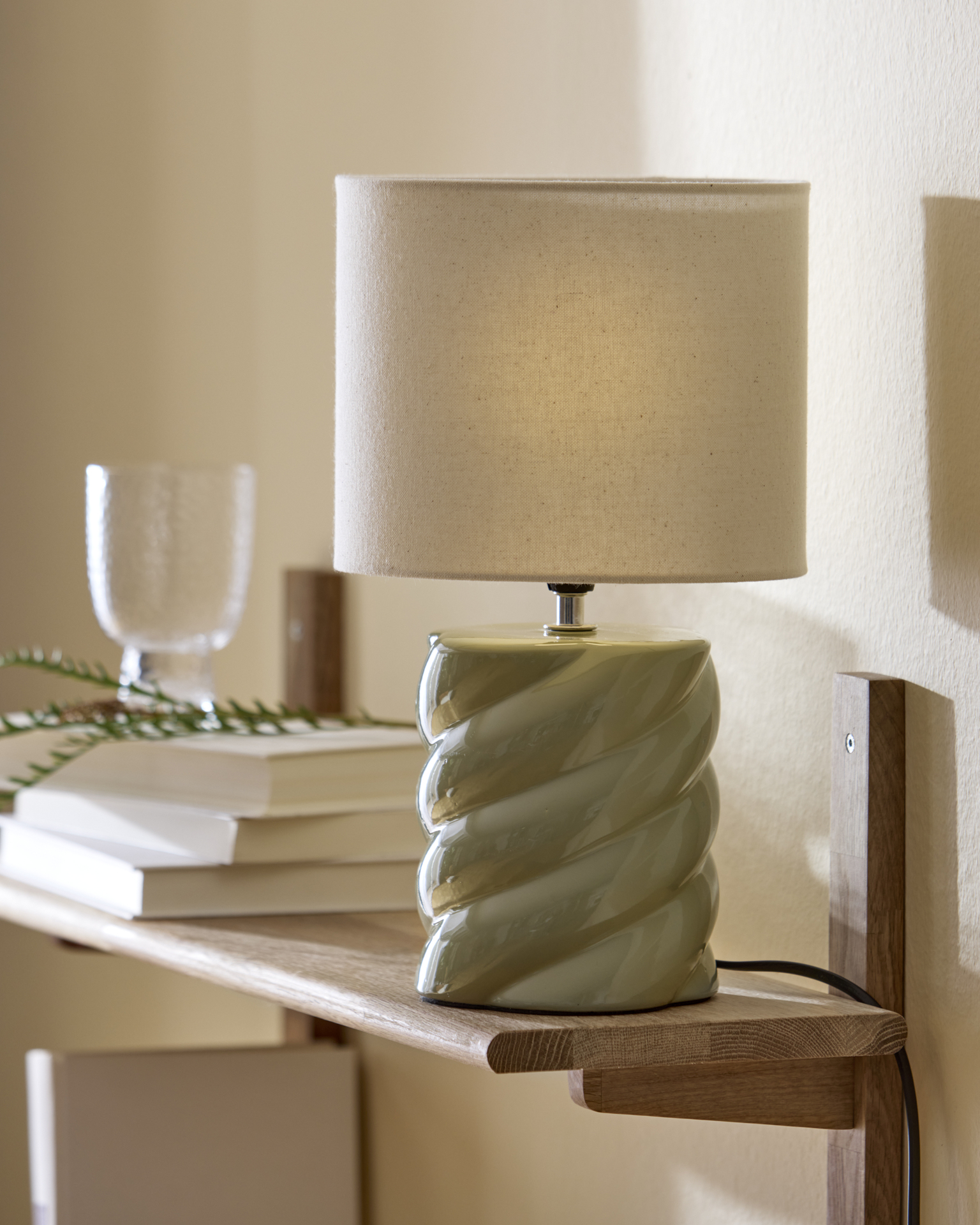 på en hylla står en ljusgrön lampfot i lekfull form 