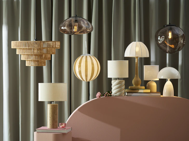 flera lampor ståendes på en rosa bord framför en grön bakgrund