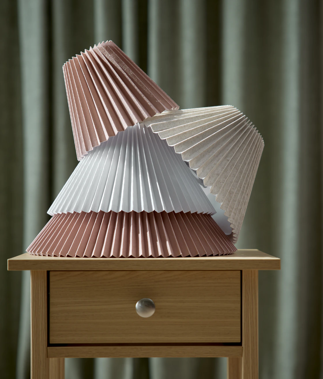 På ett sängbord är flera plisserade skärmar i olika färger och storlekar staplade