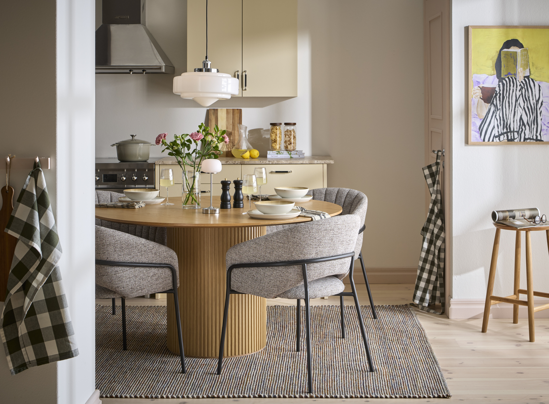 Ett runt ekbord och fyra tygklädda gråa stolar står i ett ljusgult kök.