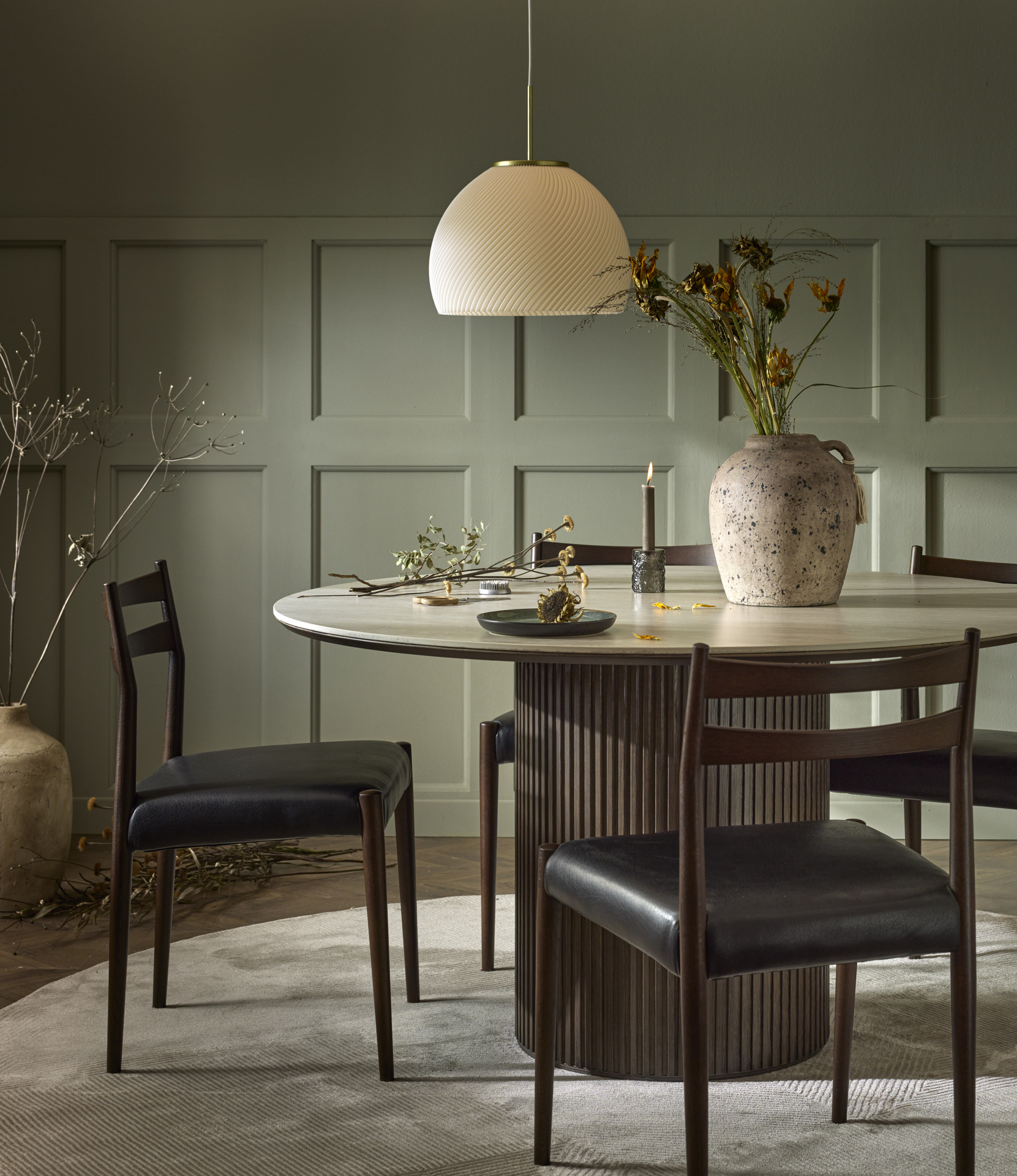 Ett runt bord och fyra stolar i mörkt trä står i ett rum med gröna väggar.