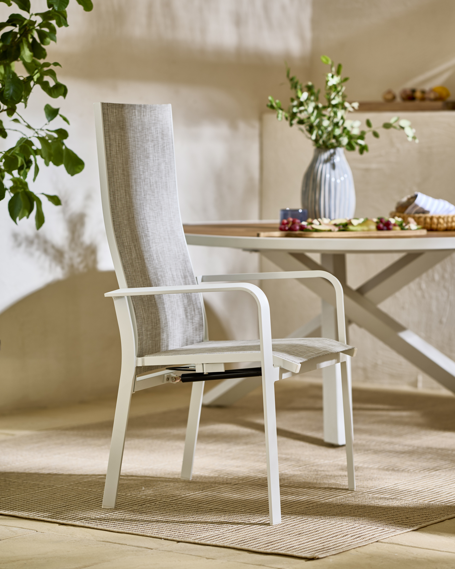 En grå och vit reclinerstol står på en utematta.