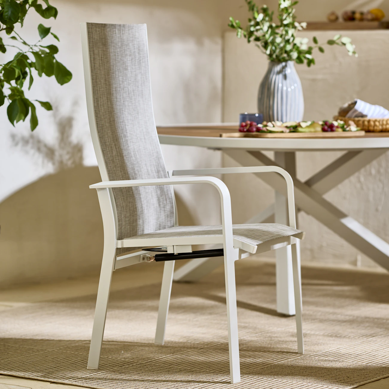 En grå och vit reclinerstol står på en utematta.