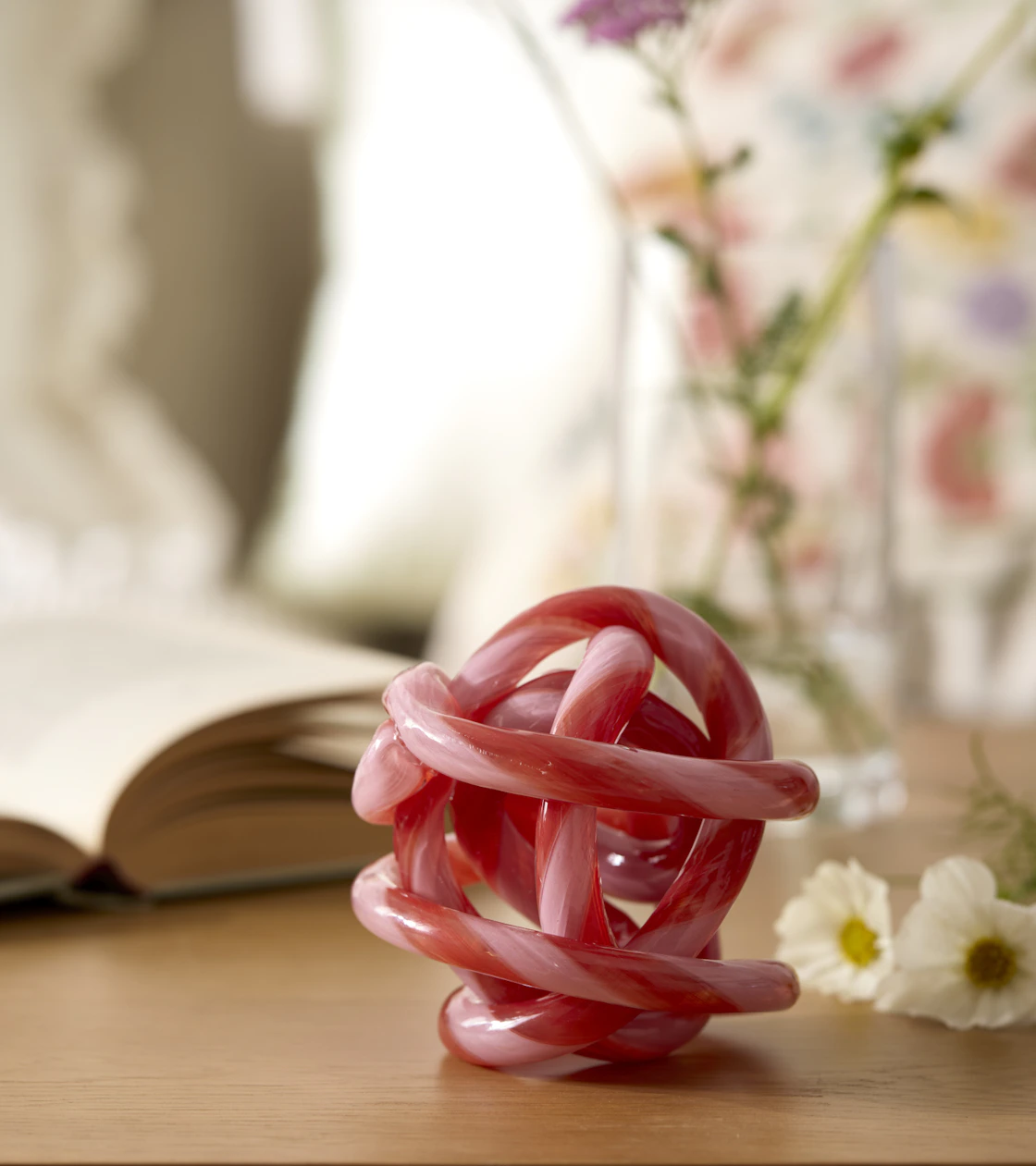 Ett rosa prydnadsföremål formad som en knut står på en skänk.