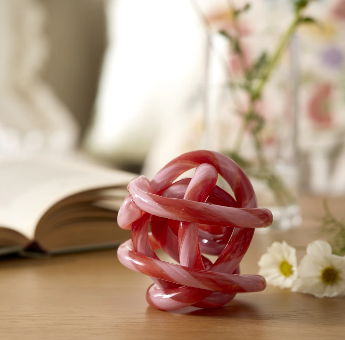 Ett rosa prydnadsföremål formad som en knut står på en skänk.