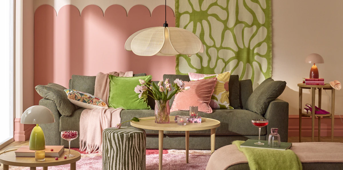 I ett färgglatt vardagsrum står en mörk soffa bakom ett ljust soffbord i trä