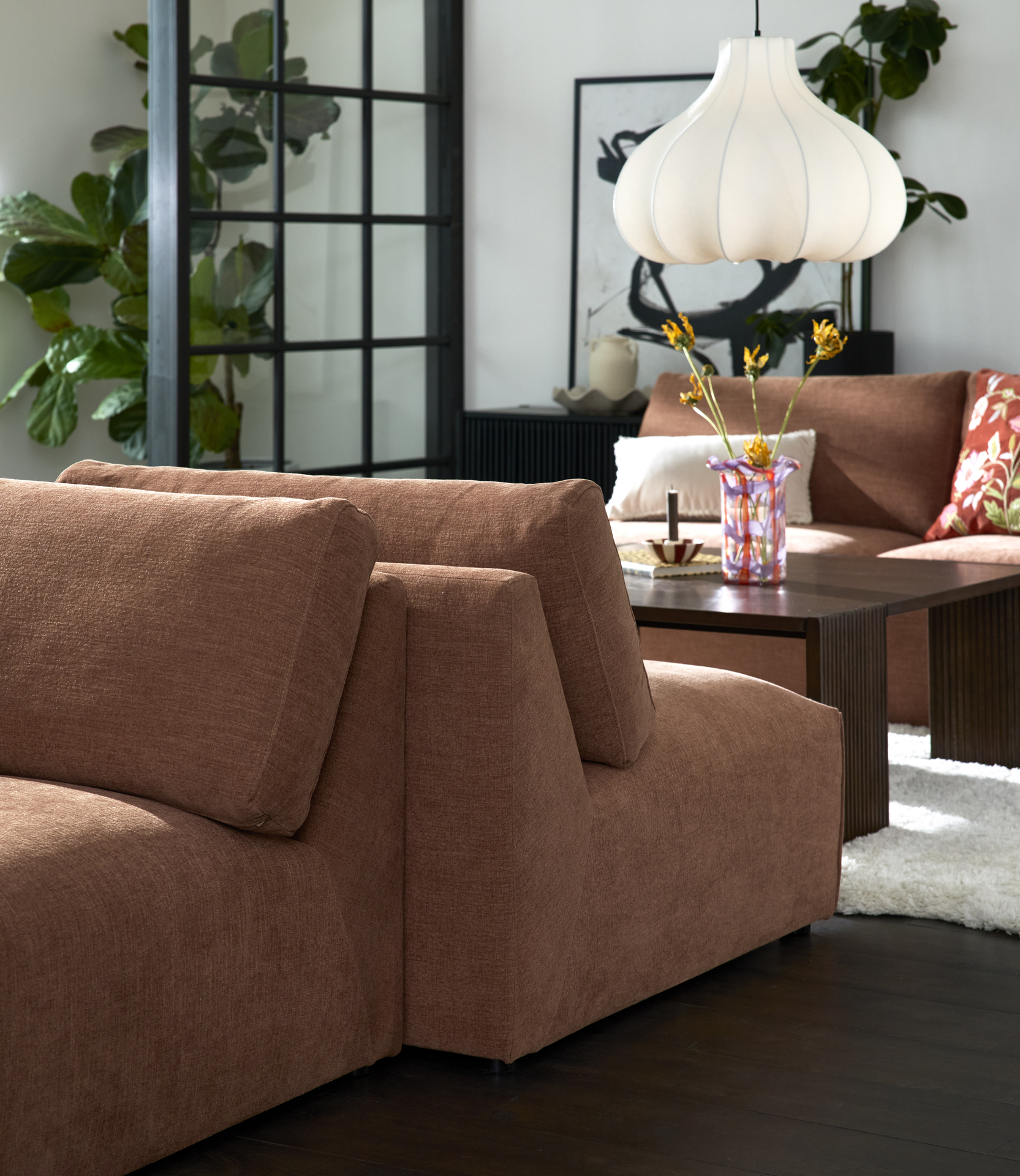 I ett vardagsrum står två rostfärgade soffmoduler rygg mot rygg