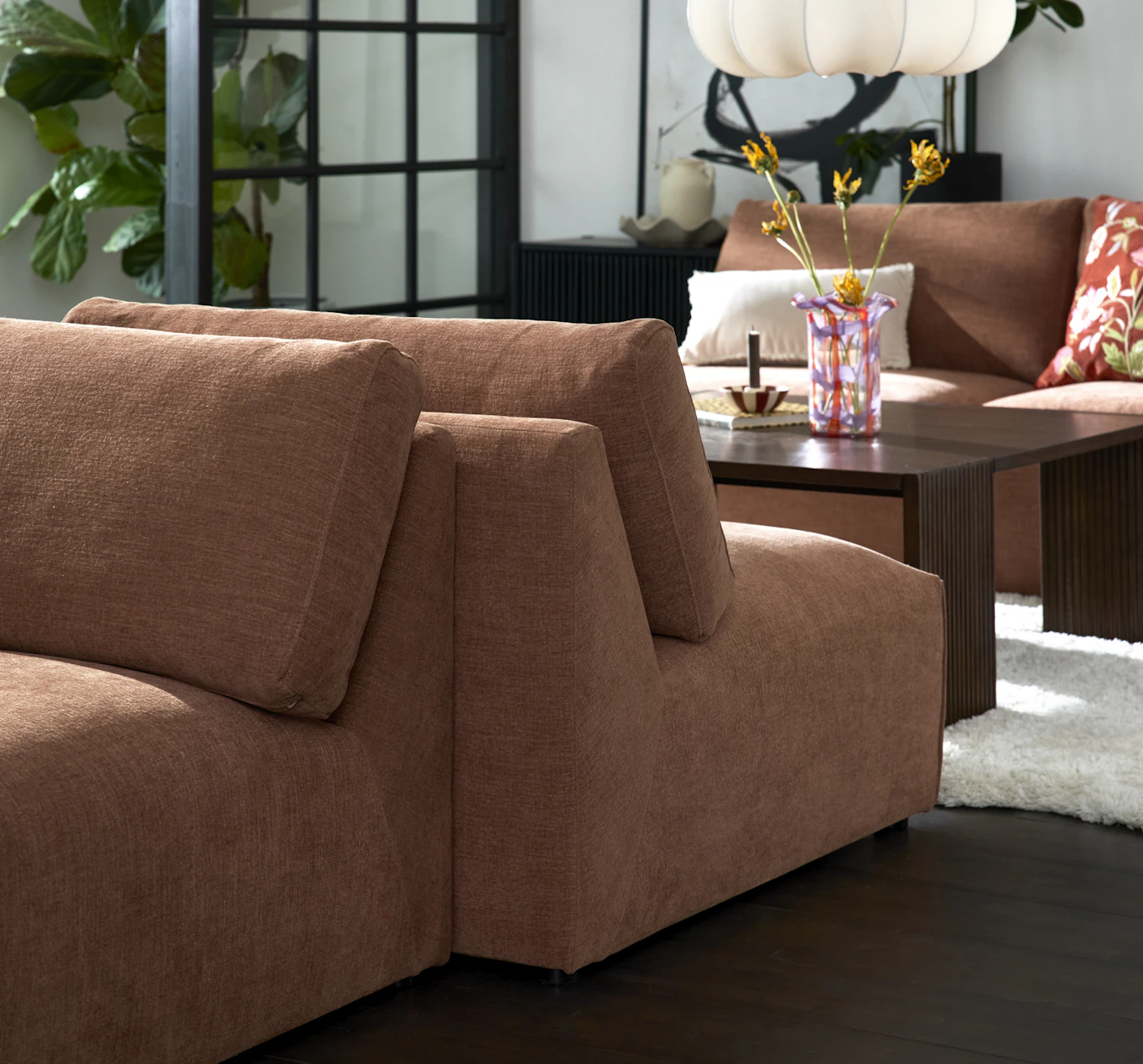 I ett vardagsrum står två rostfärgade soffmoduler rygg mot rygg