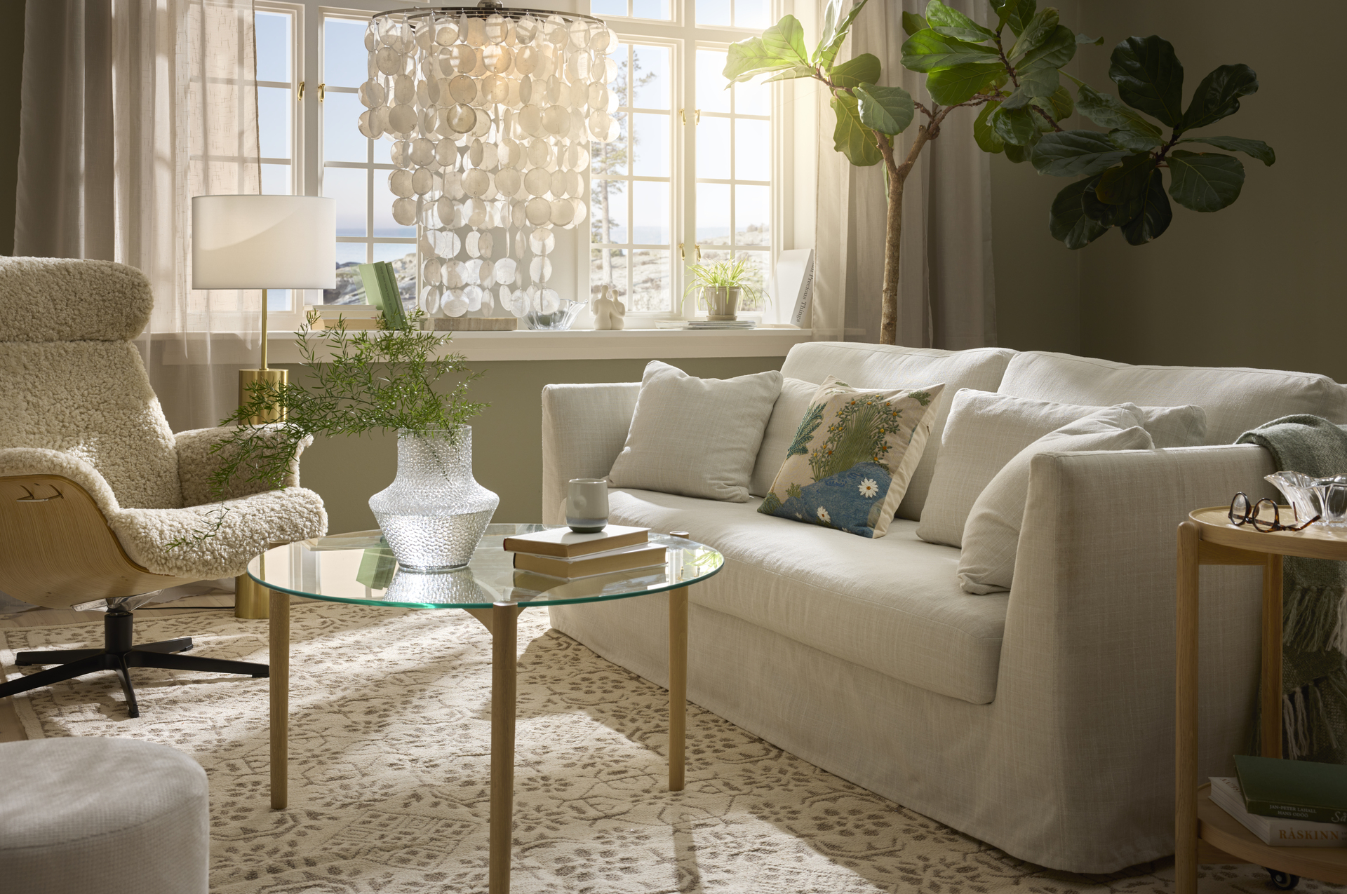 I ett vackert vardagsrum där solen skiner in står en vit Willow soffa med kappa.