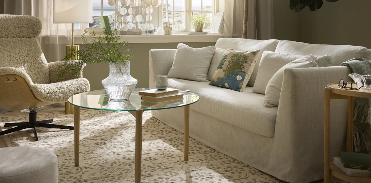 I ett vackert vardagsrum där solen skiner in står en vit Willow soffa med kappa.